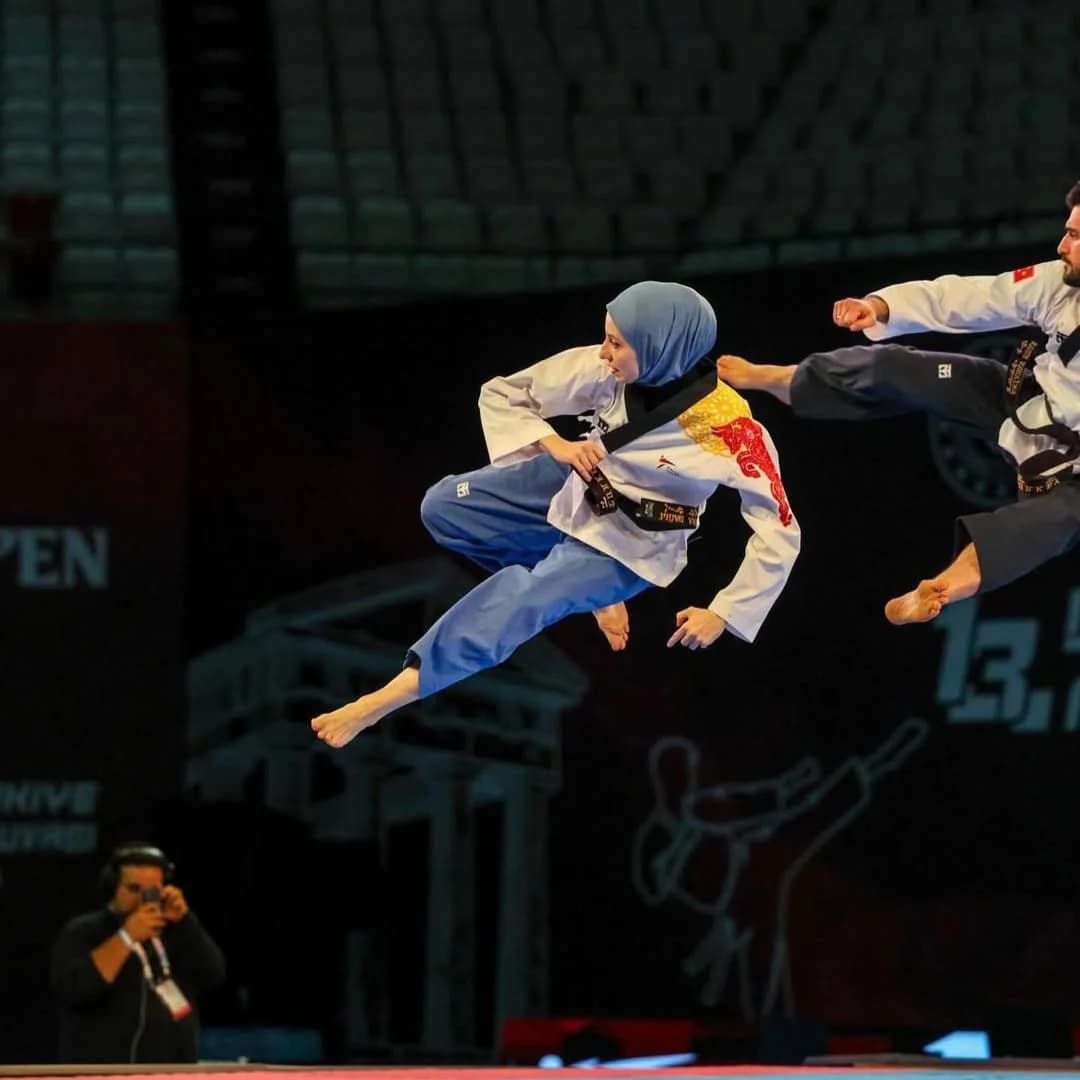 Taekwondo müsabaka alanında havada teknik uygulayan sporcu