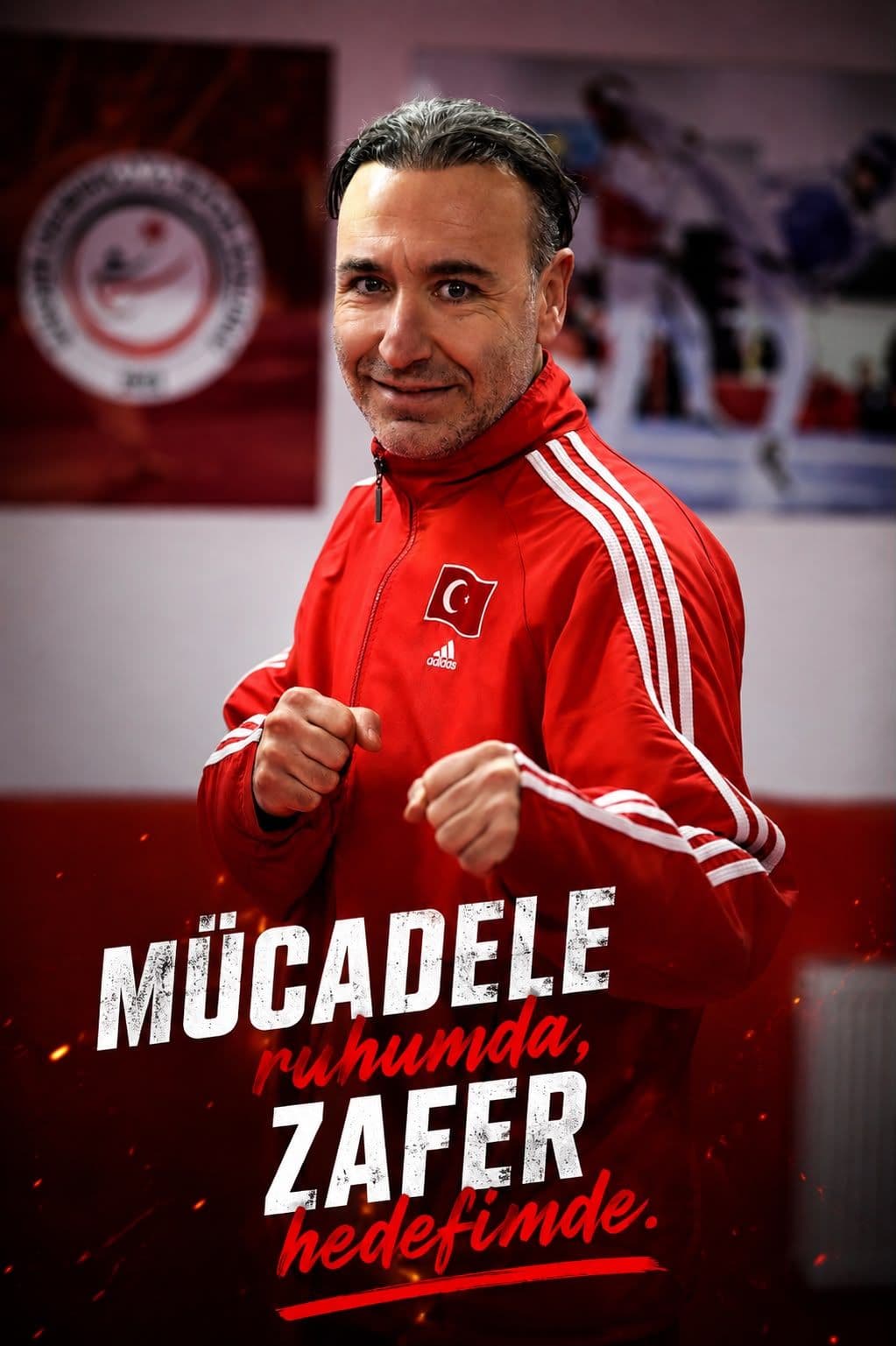 Ender Hoca, üzerinde Türk bayrağı bulunan kırmızı milli takım eşofmanıyla